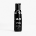 A bottle of Domi Skin Charcoal Facial Cleanser on a light gray background. The bottle is black with a black cap and a black label featuring white text.