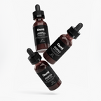 Three amber glass dropper bottles of Qforniq Vitamin C serum arranged diagonally on a light gray background.
